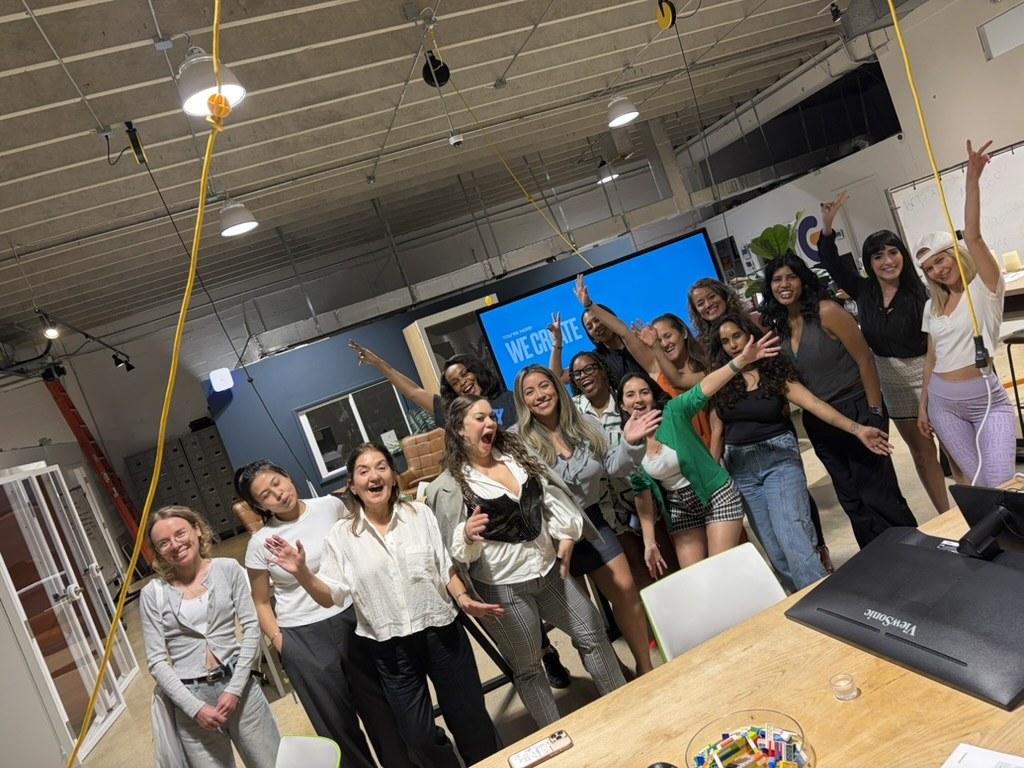 Women at a We Create build night with their hands up, celebrating